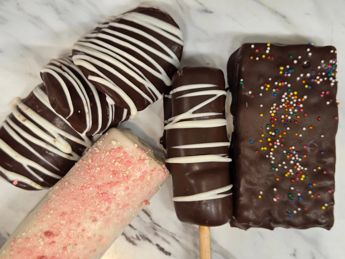 Chocolate-covered ice cream bars with white drizzle and sprinkles