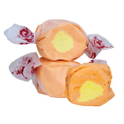 Taffy Mango: orange and yellow taffy in white paper with red florals