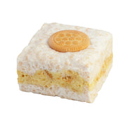 Square piece of cake with a cookie on top against a light gray background